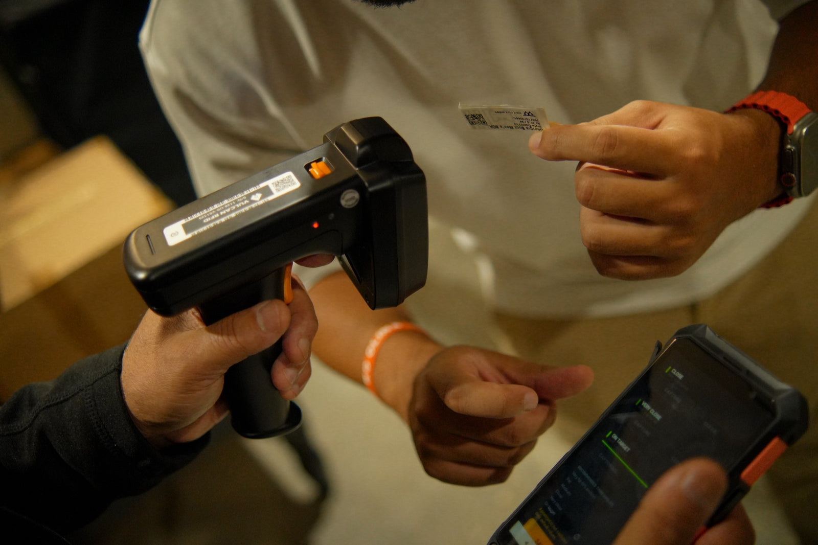 A handheld RFID reader and the PillarTrak app being used together on a warehouse floor
